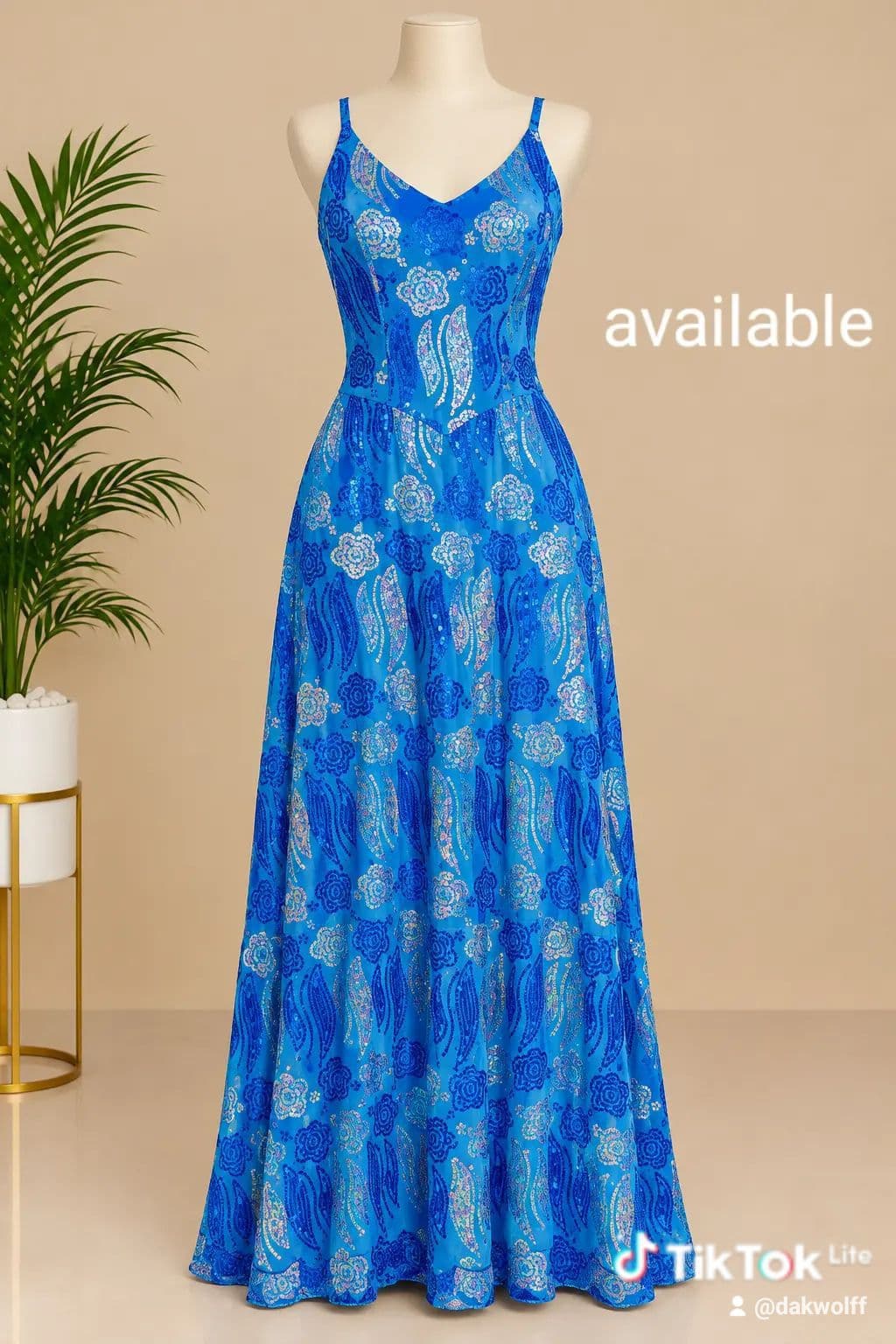 long blue maxi dress with a V-neck, thin adjustable straps and a flowing A-line skirt, decorated all over with sequin floral and swirl patterns.
• Colour: bright royal blue base with darker blue and silver-white sequin motifs
• Shape: fitted bodice with a V-neckline and thin shoulder straps
• Skirt: full, flowing A-line that falls to the floor
• Finish: sequins stitched in a floral and leaf pattern across the whole dress
• Good for: evening events, parties and weddings where you want to stand out